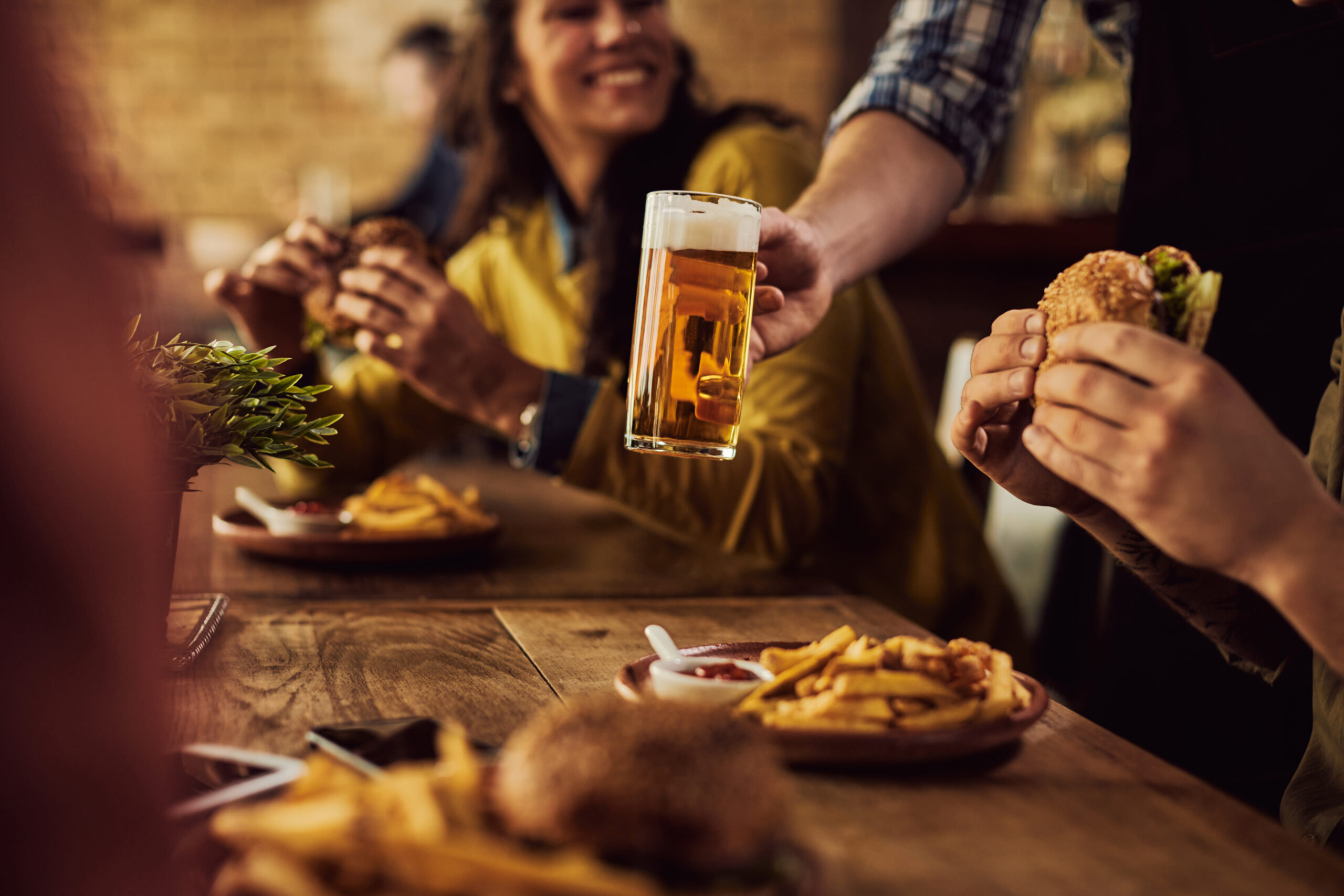 Close-up of waiter serving beer to customers who are having lunch in a pub.